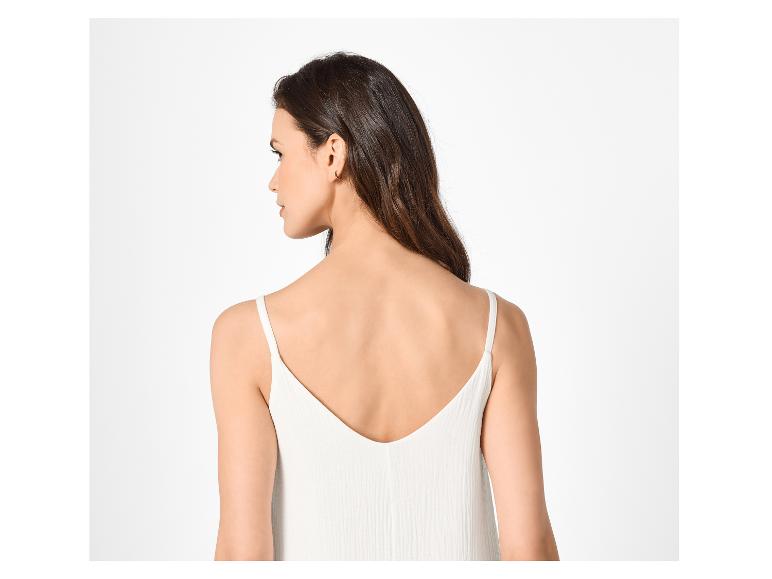 Vrouw met donker haar en witte spaghettibandjes top, van achteren gezien.