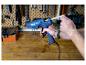 Man laadt een blauw LIVARNO® Klebepistole »EG340« met een lijmstick in een werkplaats.
