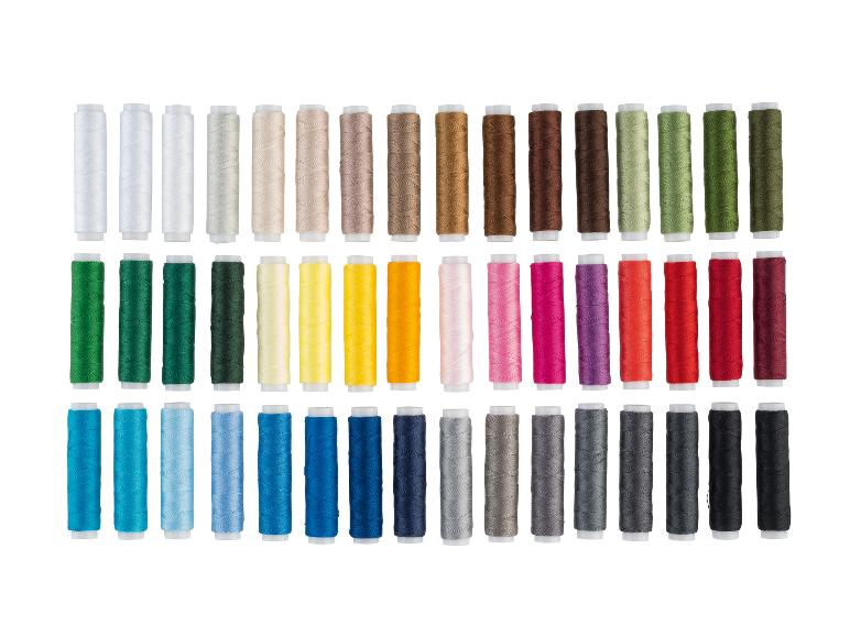 Een groot assortiment kleurrijke naaigarens gerangschikt in rijen op kleur.