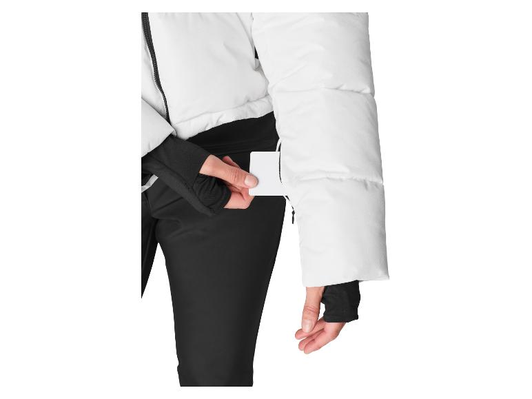Vrouw in witte jas en zwarte broek haalt een kaart uit een zak.