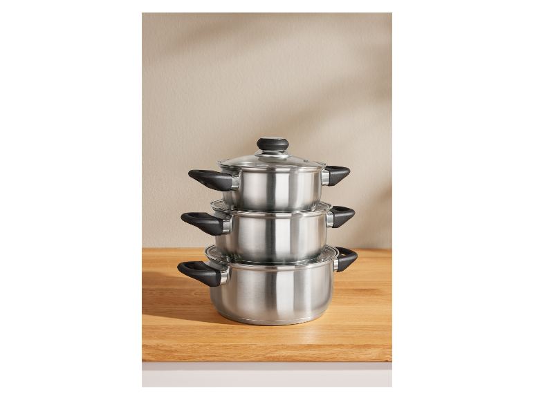 Drie gestapelde roestvrijstalen pannen met glazen deksels.