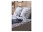 Bed met grijs frame, blauw-wit palmblad beddengoed en een blauwe deken.