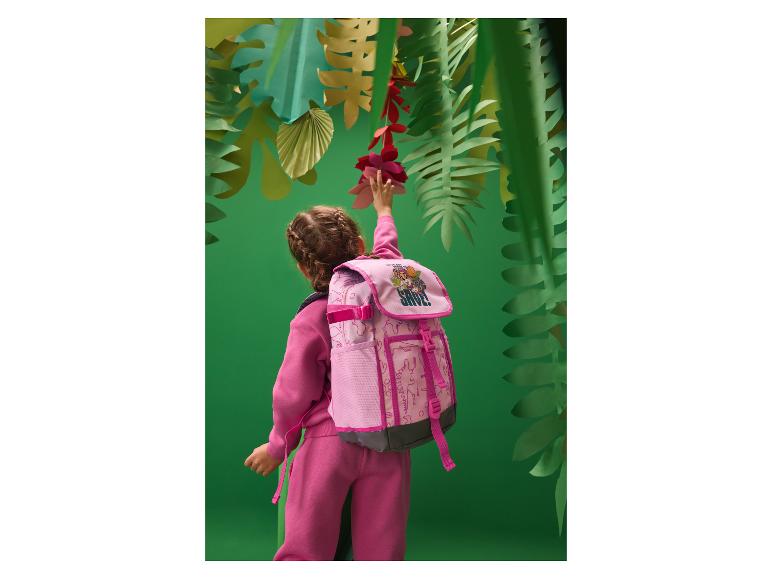 Meisje in roze trainingspak en rugzak reikt naar papieren bloemen in jungle-omgeving.