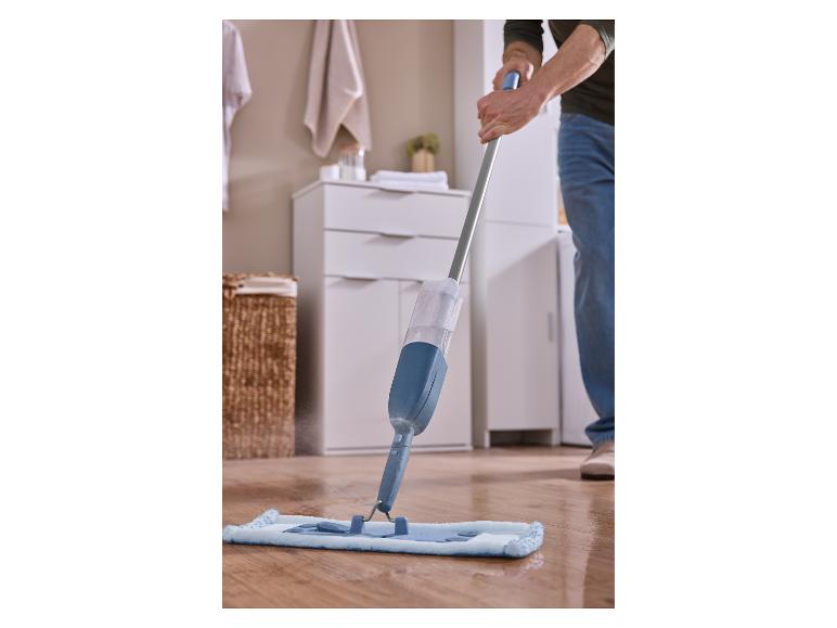 Man maakt houten vloer schoon met blauwe sproeimop.