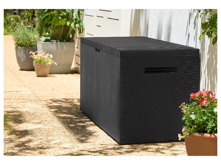 Zwarte opbergbox met rotanlook op een terras met potplanten.