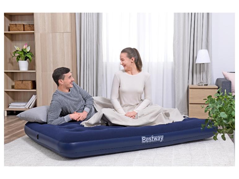 Lachend stel ontspant op een blauw Bestway luchtbed op de woonkamervloer.