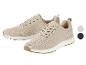 Twee beige gebreide sneakers met witte zolen en bruine accenten, met kleurstalen ernaast.