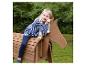 Blond meisje zit op een houten speelgoedpaard buiten.