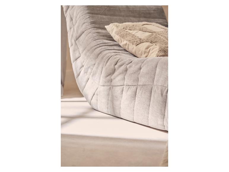 Grijze gewatteerde bank met een beige decoratief kussen.