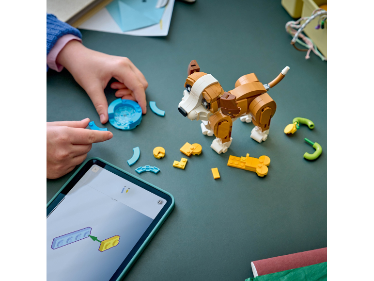 Een kind bouwt een speelgoedhond van bouwstenen met behulp van instructies op een tablet.