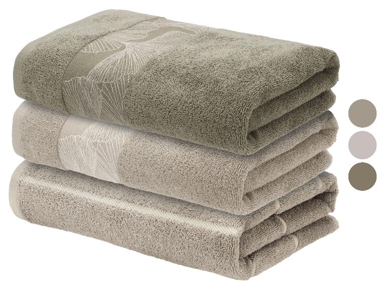 Stapel beige en olijfgroene katoenen handdoeken met bladpatroon, met kleurstalen.