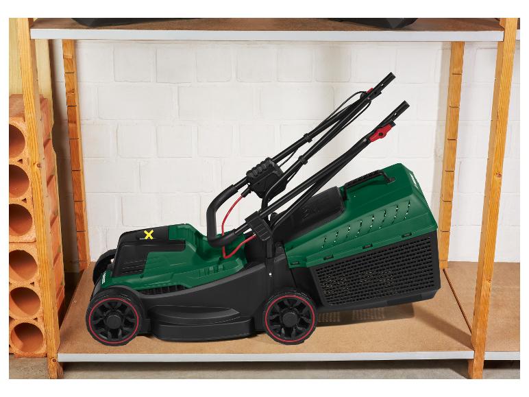 Groene Parkside grasmaaier op een houten plank in de garage.