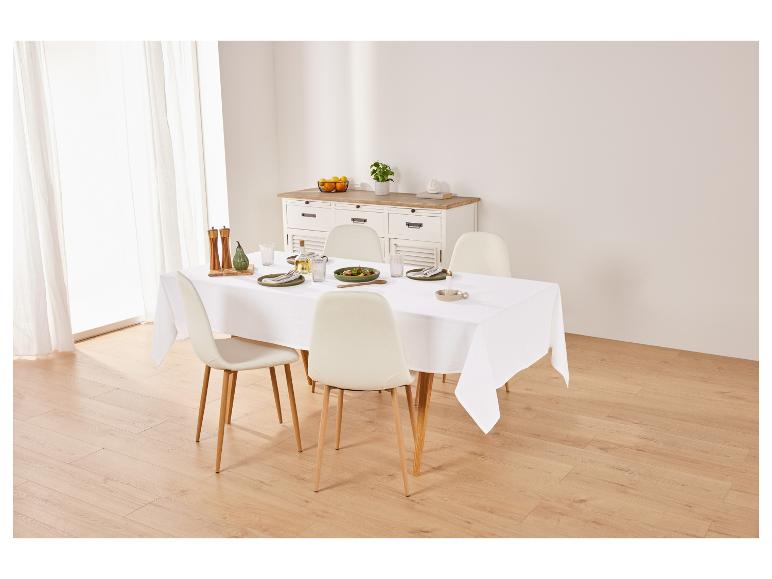 Moderne eettafel met witte stoelen en een wit tafellaken.