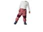 Kind in wit shirt en roze broek met donkerblauwe laarzen.