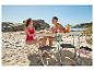 Paar op strand met klaptafel, fruit en waterfles.