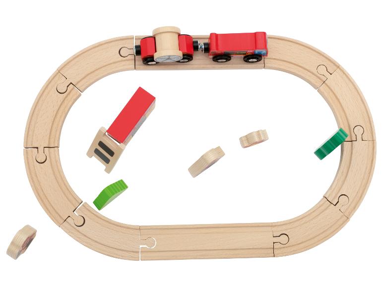 Houten treinbaan met een rode trein en losse onderdelen op een witte achtergrond
