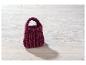 Handgebreide bordeauxrode handtas op wit hout.