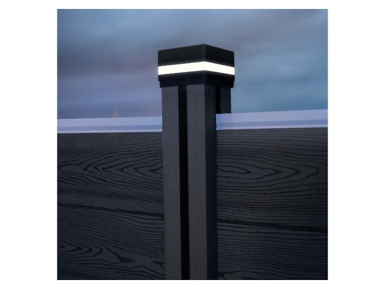 Verlichte schuttingpaal met donkere houten panelen en een heldere lucht op de achtergrond.