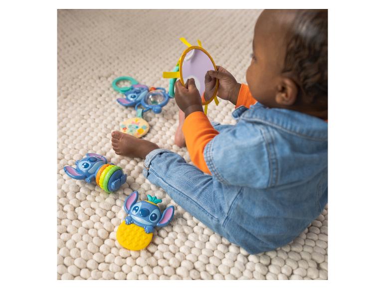 Baby speelt met tekenfilmfiguren en een spiegel op een vloerkleed.