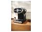 Zwart en zilveren espressomachine op een houten aanrecht met koffiebonen.