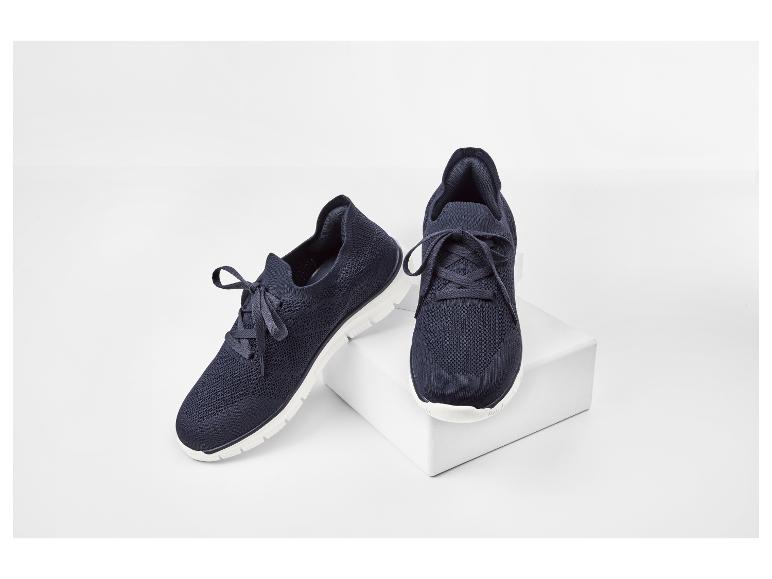Een paar donkerblauwe sportschoenen met witte zolen op een witte achtergrond.