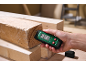 Hand houdt vochtmeter tegen houten balk, toont 0,0% vocht.