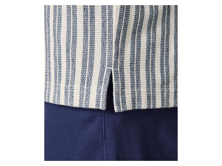 Close-up van een blauw-wit gestreepte top met zijsplit, gecombineerd met een marineblauwe broek.