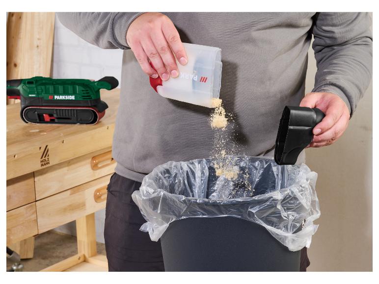 Een persoon leegt zaagsel van een Parkside schuurmachine in een vuilnisbak.