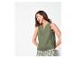 Vrouw in groene mouwloze top en bedrukte shorts, lachend en naar links kijkend.