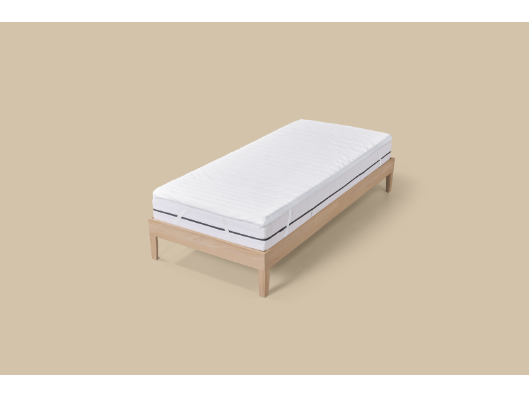 Wit matras op houten bedframe op beige achtergrond.