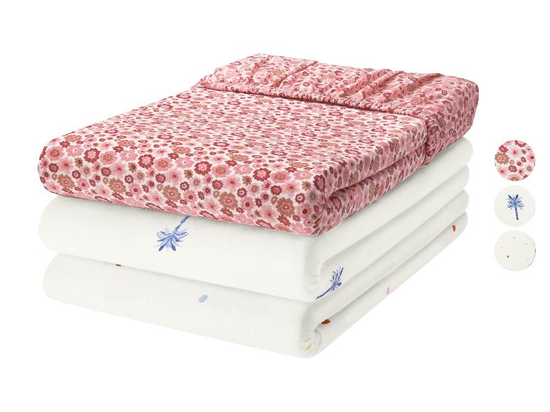 Katoenen beddengoedset met roze bloemenprint en witte lakens met palmbomen en stippen.