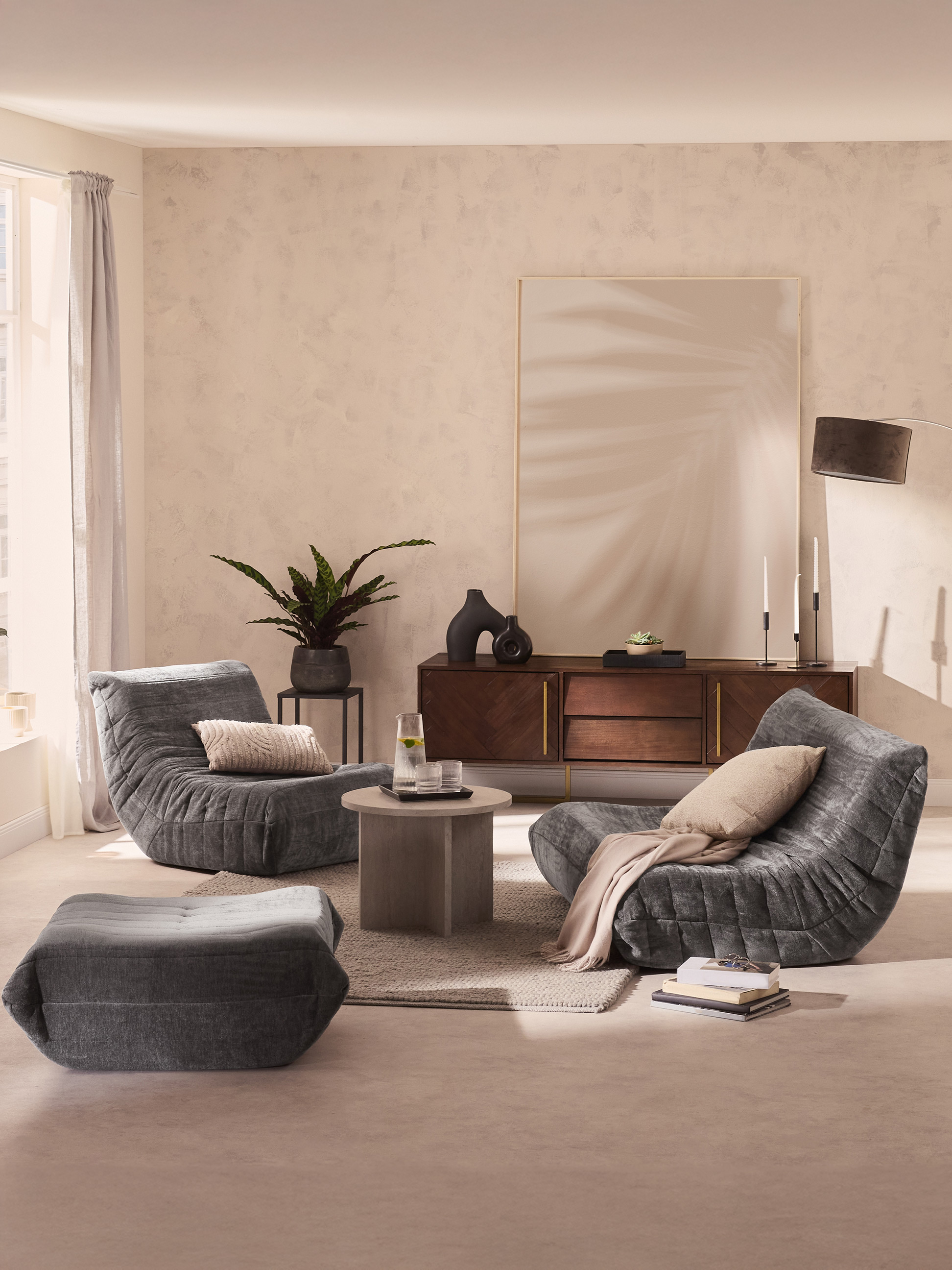 Moderne woonkamer met comfortabele grijze fauteuils, salontafel en houten dressoir.