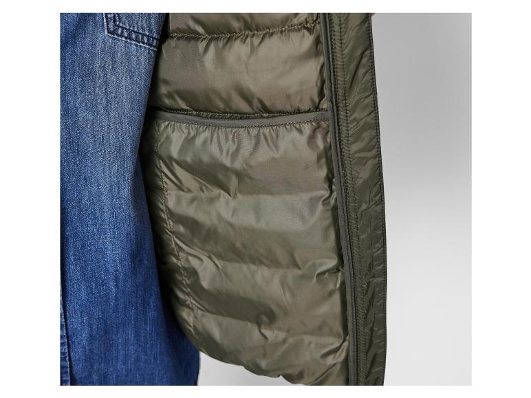 Detail van een groene gewatteerde jas gecombineerd met denim.