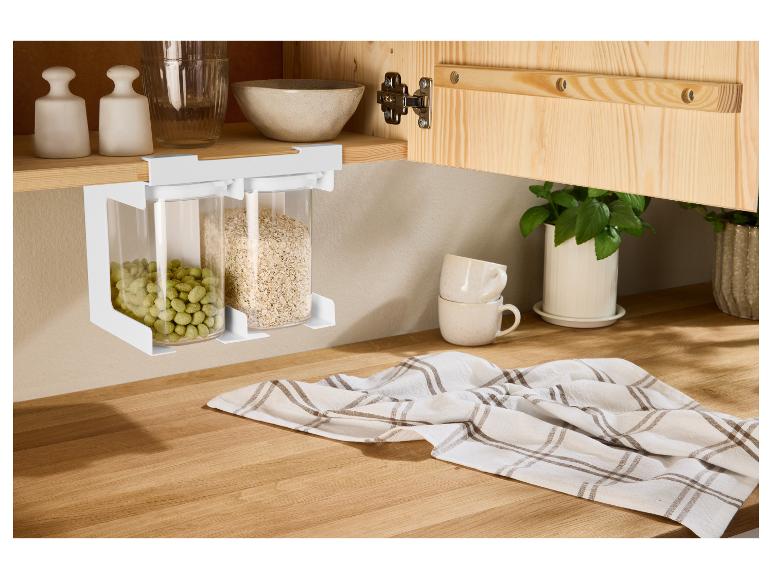 Keukenplank met twee voedselcontainers, handdoek, kopjes en planten op een houten aanrecht.