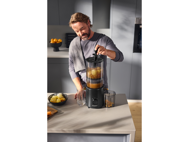 Man gebruikt een sapcentrifuge om vers sap te maken in een moderne keuken.