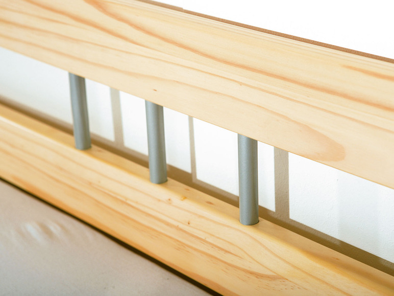 Een houten bedframe met zilveren spijlen.