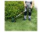 Man trimt gras met een Parkside grastrimmer, naast een groene struik.