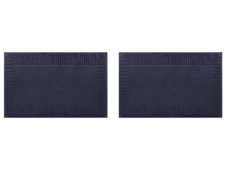 Twee marineblauwe badmatten met een getextureerd randpatroon.