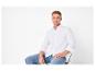 Man in wit overhemd en jeans zittend op een stoel.