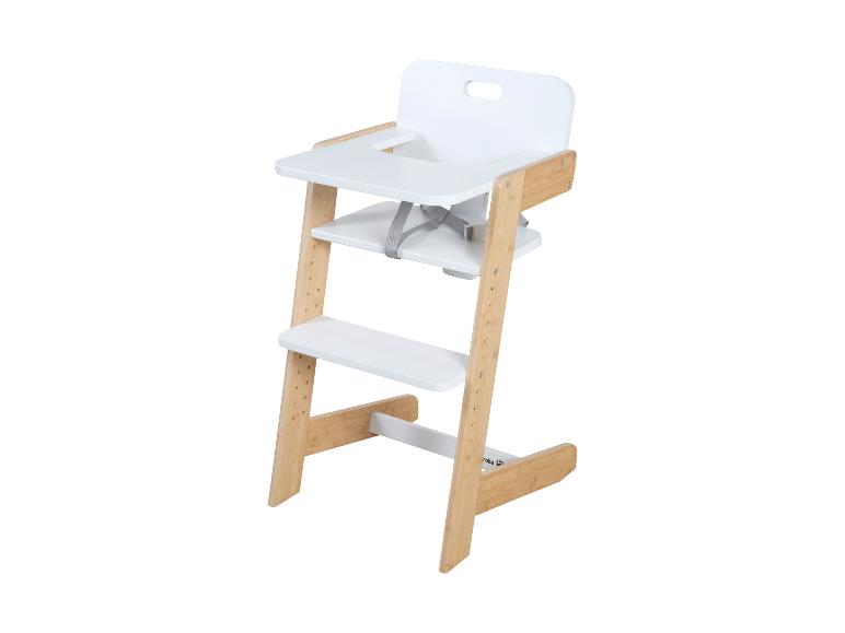 Houten kinderstoel met witte zitting en dienblad, voorzien van een grijs veiligheidsharnas.