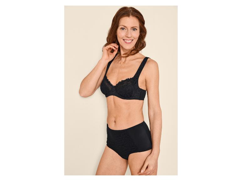 Lachende vrouw in zwarte beha en slip met bloemenpatroon.