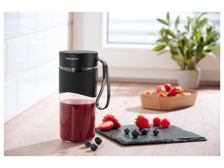 SilverCrest draagbare blender met rode smoothie en vers fruit op een houten plank.