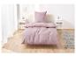 Roze beddengoed op een bed in een lichte slaapkamer.
