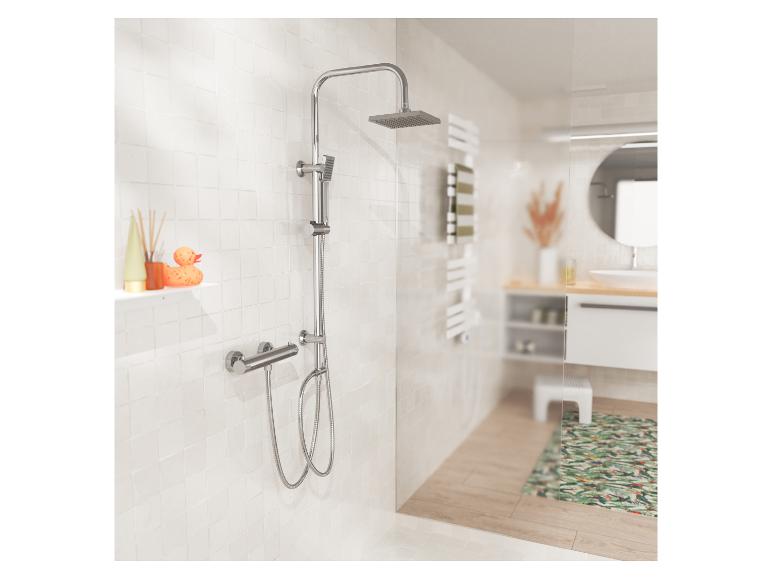 Chromen doucheset met regendouche en handdouche, op witte tegels in de badkamer.