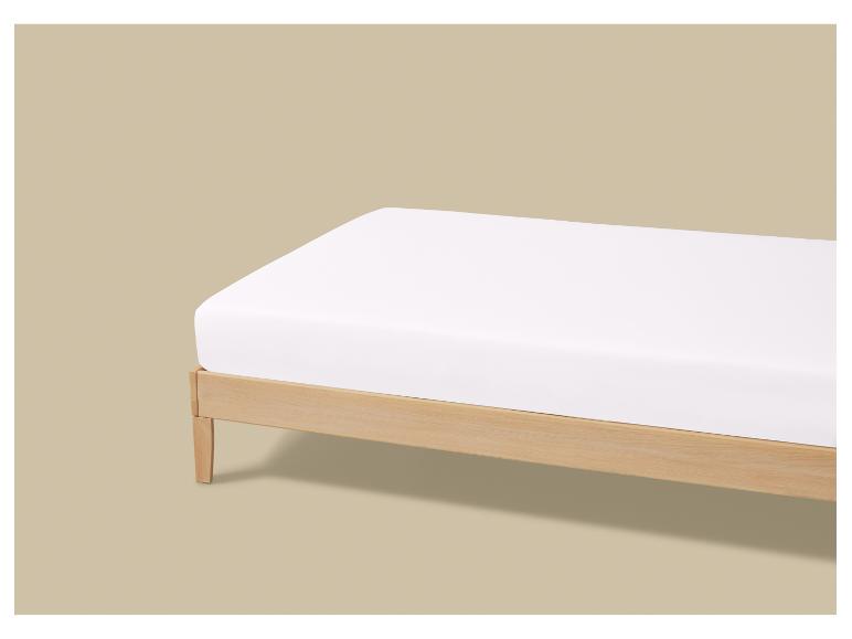 Houten bed met een wit matras op een beige achtergrond.