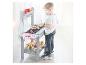 Jongen speelt met een houten speelgoedbarbecuekeuken, met speelgoedeten en accessoires.