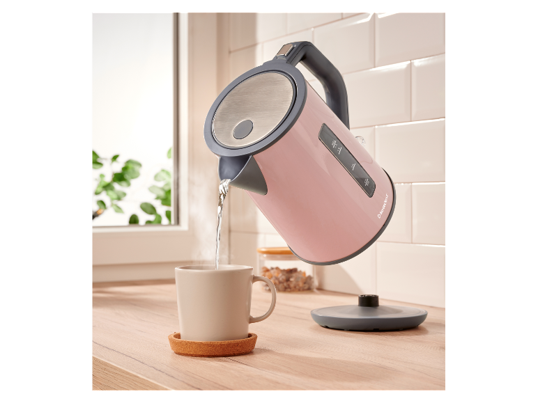 Een roze SilverCrest waterkoker giet water in een mok.
