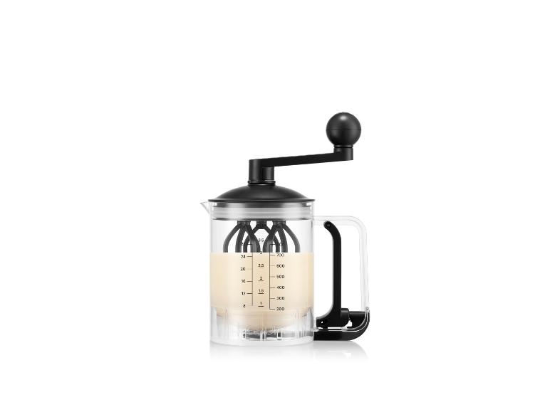 Een heldere glazen handmatige melkopschuimer met een zwart handvat en deksel, met een lichtgekleurde vloeistof.