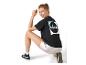 Vrouw in een zwart T-shirt met holografische print en zilveren shorts, gehurkt.