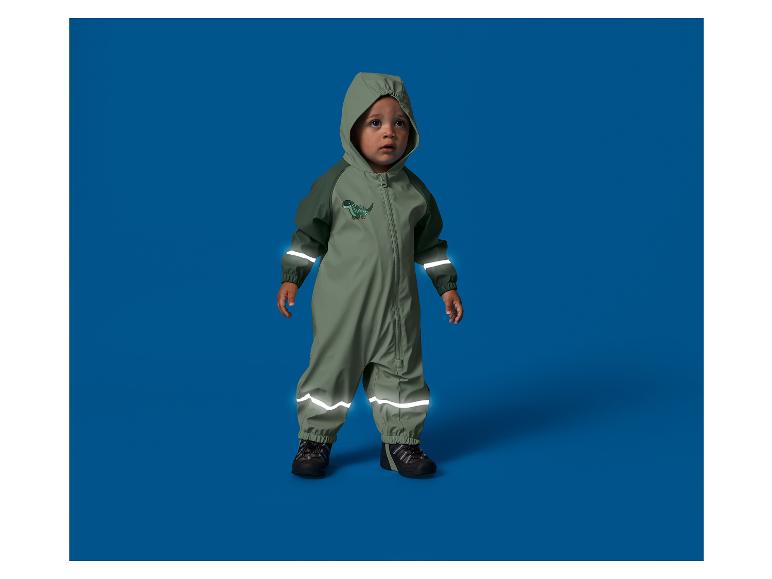 Peuter in een waterdicht pak met capuchon en reflecterende strepen, met een dinosaurus.